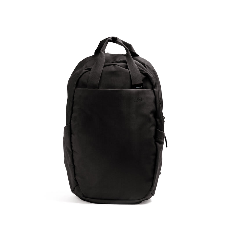 The Resmed Luxe, A black nylon backpack with dual top handles, a front slip pocket, and zippered side pockets, photographed against a solid white background.