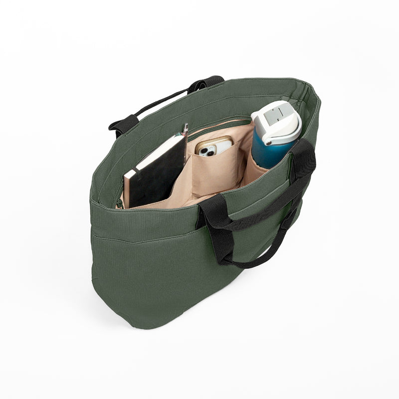 Luxe Tote bag, the olive green canvas tote bag shown from an overhead angle, filled with a notebook, a smartphone, and a blue water bottle, on a clean white background.