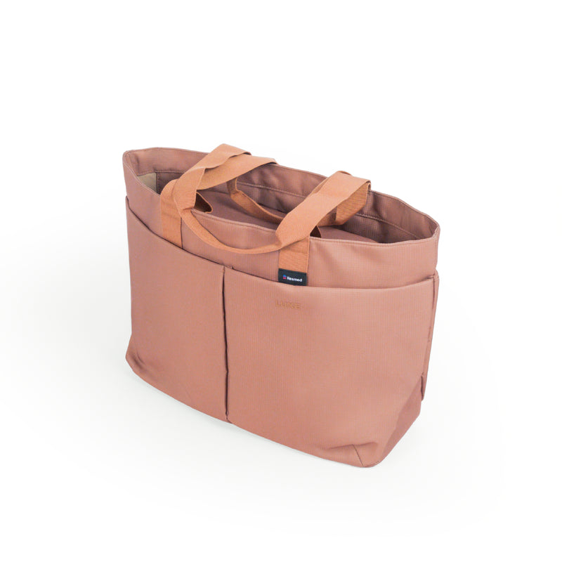 Luxe tote, A dusty rose tote bag with dual top handles and front utility pockets, shown from a three-quarters angle on a clean white background.