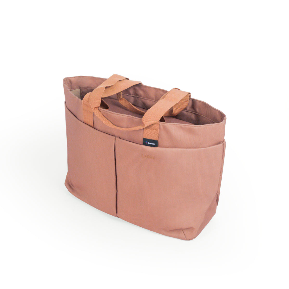 Luxe tote, A dusty rose tote bag with dual top handles and front utility pockets, shown from a three-quarters angle on a clean white background.
