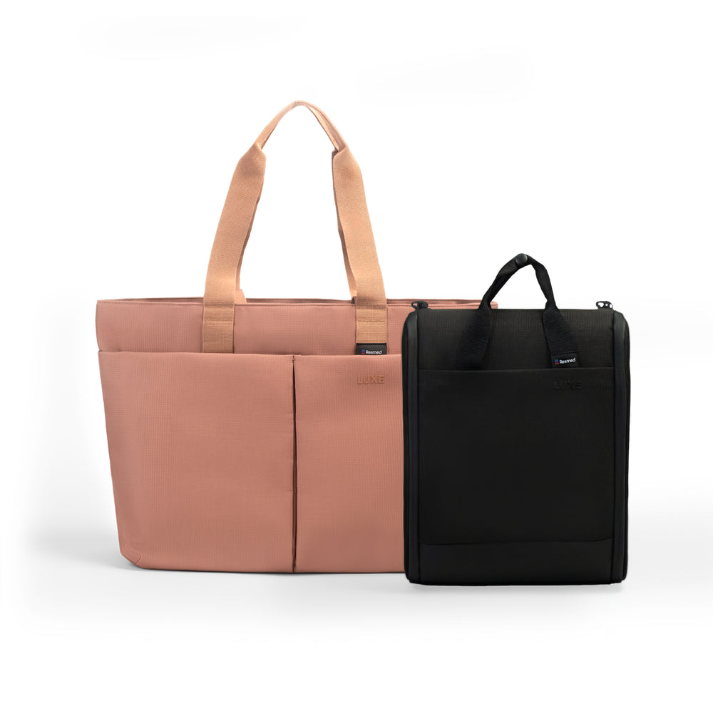 A pink tote luxe bag and a white cpap insert bag next to each other. The larger bag is rose pink with black handles and front seam detailing.